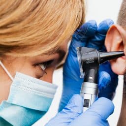 Audiologist examining a man's ear.